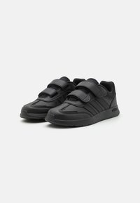 Baskets de sport noires avec des bandes Velcro, tige en synthétique, accents texturés et semelle en caoutchouc. Arbore un design à trois bandes.