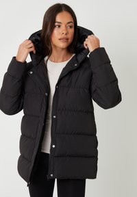 Sort pufferjakke med hætte, der har en quiltet design, lynlås og trykknapper. Glat tekstur og mellemlangt design, velegnet til koldt vejr.