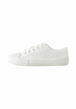 White low-top sneaker with textured sole, lace-up closure, and raised dot pattern on side and toe cap against white background.