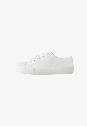 White low-top sneaker with textured sole, lace-up closure, and raised dot pattern on side and toe cap against white background.