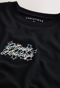 Sudadera negra con texto bordado "Felices Fiestas" entrelazado con patrones de luces coloridas. Diseño de cuello redondo con textura suave.