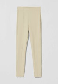 Leggings beige con canalé y un diseño ajustado, que presentan una cinturilla elástica y una textura suave, ideales para el uso diario.