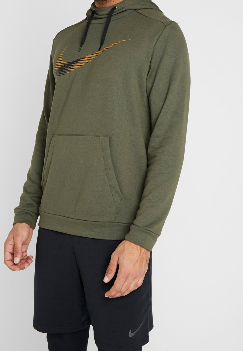 Sweat à capuche vert olive avec accents noirs, doté d'un grand logo Nike rayé, d'une capuche ajustable avec cordon de serrage et d'une poche kangourou à l'avant.