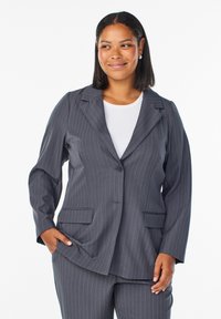 Blazer de rayas en gris oscuro con solapa de muesca, cierre de un solo botón y dos bolsillos frontales. Mangas largas con ajuste relajado.