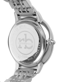 Baksidan av en rostfri klocka med en slät, reflekterande yta med ingraverad logotyp, vattentålig indikator och modellnummer.