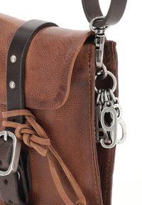 Brązowa skórzana torba o teksturowanym wykończeniu, z klamrą, skórzanym paskiem i metalowymi elementami. W zestawie znajduje się dekoracyjny srebrny charms.