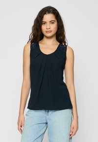 Haut sans manches bleu marine avec des plis et des accents en dentelle sur les épaules. Tissu doux avec un col rond, offrant une coupe décontractée.