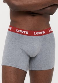 Szürke pamut boxeralsó, szoros illeszkedéssel, piros, "Levi's" felirattal, fehér betűkkel domborítva.