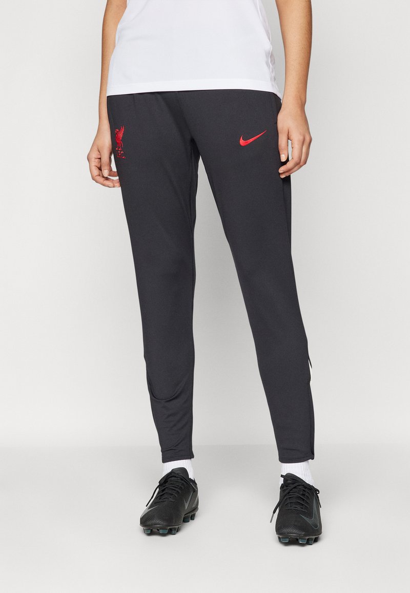 Juodi sportiniai kelnių modeliai su prigludusia išvaizda, turintys raudoną „Liverpool FC“ logotipą ir raudoną „Nike“ ženklą. Pagaminti iš sklandžios, lengvos medžiagos.
