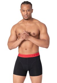 Melni boksa apakšveļas, ar sarkanu jostu, uz kuras ir uzraksts "MUCHACHO MALO." Audums šķiet gluds, ar priekšējām šuvju detaļām.