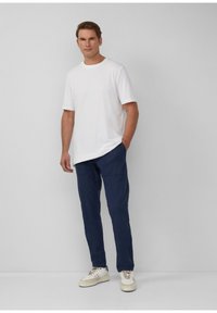 Weißes Rundhals-T-Shirt, marineblaue Cargo-Hosen mit Seitentaschen und weiße Sneaker. Lässiger Schnitt, minimalistisches Design, Baumwollmischgewebe.