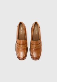 Brune lær loafers med en glat finish, som har et syet design og en frontstrop detalje. Flad sål, rund tå og indersålsbranding.