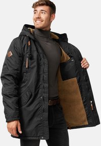 Schwarze isolierte Jacke mit Kapuze, die ein beige Fleece-Futter, braune Akzente, Reißverschlüsse und Druckknöpfe aufweist. Verfügt über seitliche Taschen und eine Innentasche.