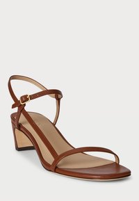 Pruun nahast kontsaga sandaalid mõõduka plokknõelaga, minimalistlik disain, õhukesed rihmad ja reguleeritav pahkluu rihm kuldsete detailidega.