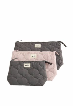 Three quilted zippered pouches in dark gray, light pink, and medium gray, each with a white label that reads "self."