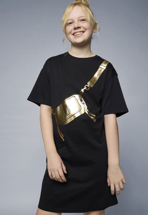 Svart t-skjortekjole med et gullmetallisk design som etterligner en crossbody-veske, med korte ermer og en avslappet passform. Glatt tekstur.