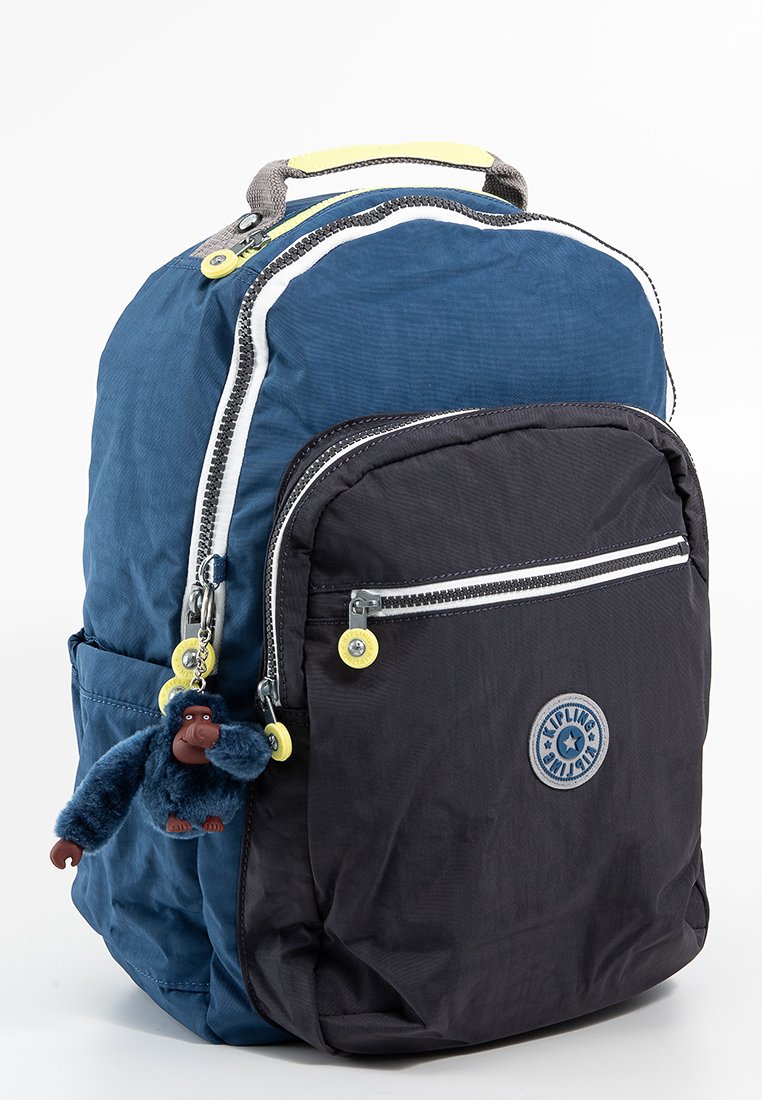 Mochila azul y negra con bolsillos con cremallera, una superficie texturizada y un llavero con forma de mono adjunto a la cremallera delantera.