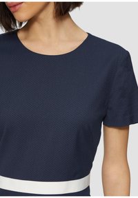 Abito blu navy con maniche corte, scollo rotondo, texture a pois e motivo a cintura bianca a contrasto in vita.