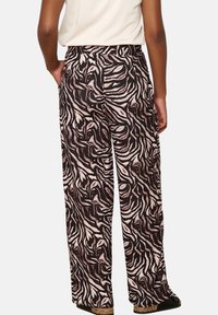 Wide-leg pants in a black, brown, and beige abstract zebra print. The fabric has a smooth texture and a fitted waist with belt loops.