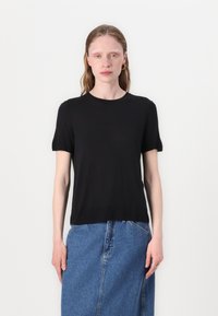 Svart kortärmad t-shirt i mjukt material med klassisk rund halsringning, tillsammans med en blå denimkjol. Enkelt och minimalistiskt design.