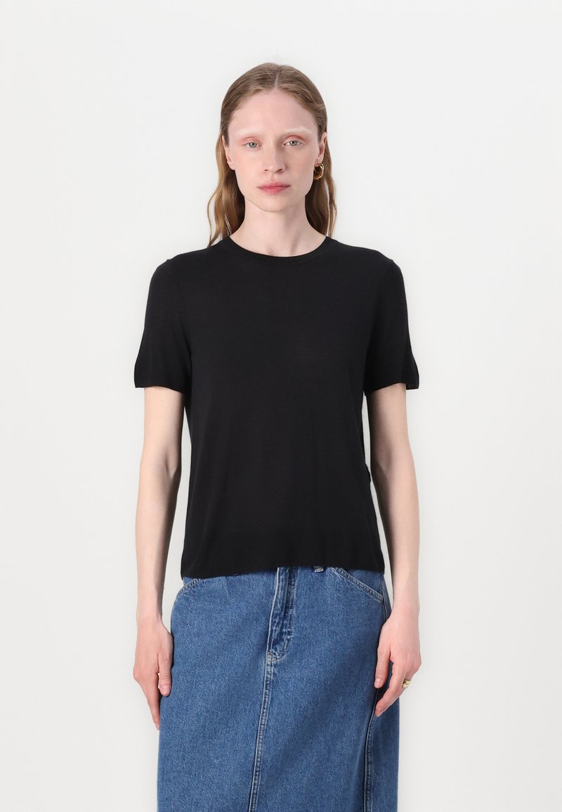 Svart kortärmad t-shirt i mjukt material med klassisk rund halsringning, tillsammans med en blå denimkjol. Enkelt och minimalistiskt design.