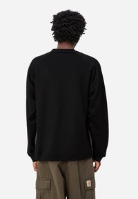 Camisa negra de manga larga con mangas raglán, confeccionada con tela de textura suave, que presenta una parte posterior lisa y un diseño sencillo.
