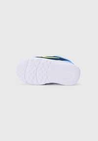 Chaussure de sport bleue avec une semelle blanche texturée et un accent vert. Dotée d'un matériau supérieur en synthétique et d'un design de bout arrondi.