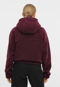 Bordeaux fleece huppari suurella hupulla, joustavalla helman ja ribatulla hihalla; siinä on teksturoitu, pehmeä pinta ja rento istuvuus.