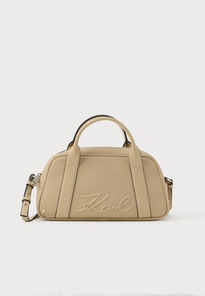 Beige handbag with dual top handles, adjustable shoulder strap, and embossed "Karl" signature on front panel, set against a white background.