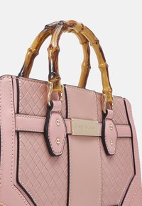 Różowa torba na ramię z pikowanym wzorem, bambusowymi uchwytami, złotym okuciem i prostokątnym kształtem. Posiada metalową tabliczkę z logo.