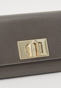 Gray textured leather wallet featuring a gold-tone metal clasp with a distinctive logo, showcasing a smooth finish and compact design.