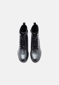 Must mustad nahkkingad musta läikiva viimistlusega. Omavad ühte narmendavat nööri külge, lukuga sulgemist ning kontrastset tekstuuri aktsenti.