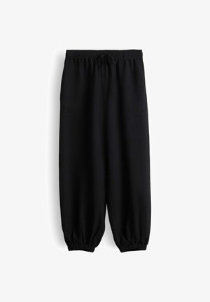 Pantaloni neri a vestibilità ampia con cintura elastica, coulisse, tasche laterali e polsini elastici alle caviglie su sfondo bianco.