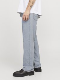 Jeans de mezclilla azul claro con un corte holgado y pierna recta, combinados con zapatos de cuero negros con una suela gruesa.