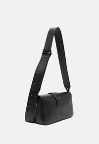 Sac à main en cuir noir avec une forme structurée, une bandoulière perforée amovible et des accents en métal doré. Présente une fermeture à rabat avec un détail en logo.