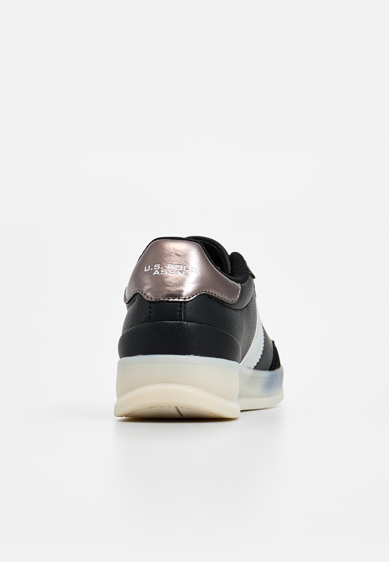 Zapatilla en blanco y negro con un acento metálico en rose gold en el talón, que presenta una textura suave y una suela de goma translúcida.