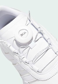 Sneaker bianca con tomaia sintetica liscia, accentuata da un sistema di chiusura BOA e lacci grigi. Cuciture dettagliate lungo i bordi.