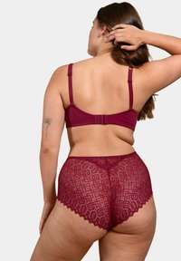 Ensemble de lingerie bordeaux comprenant un bralette lisse avec des bretelles réglables et un short en dentelle assorti avec des motifs géométriques et des bords festonnés.