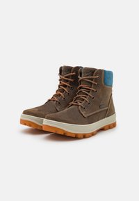 Botas de senderismo marrones con parte superior de cuero, acentos de ante azul, cordones naranjas y suelas de goma. Diseñadas para la durabilidad y tracción.