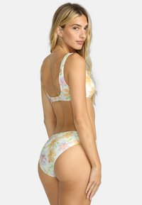 Blommig bikini-set i en pastellfärgpalett. Har en topp med scooped halsringning och högskurna underdelar, båda prydda med ett subtilt blommönster.