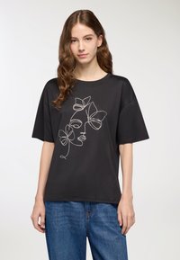 T-shirt nera a maniche corte con un design in linea bianca che rappresenta un volto e dei fiori. Materiale in cotone texturizzato, vestibilità rilassata e scollo a girocollo.