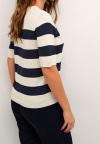 Gestreifter Strickpullover in Marineblau und Creme mit geripptem Ausschnitt und kurzen Ärmeln. Der Pullover hat einen geraden Schnitt und eine glatte Textur.