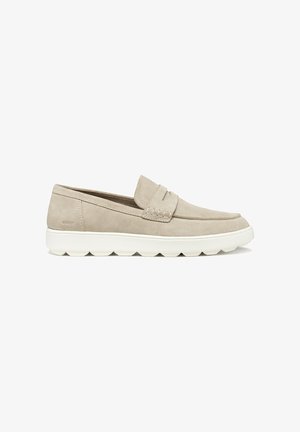 Mocassini slip-on in camoscio beige con suola piatta bianca, caratterizzati da un dettaglio cucito sulla parte frontale. Design semplice senza elementi metallici visibili.