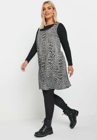 Ärmelloses Kleid mit Tierdruck in Grautönen, aus leichtem Stoff. Kombiniert mit schwarzen Leggings und klobigen schwarzen Schnürstiefeln.