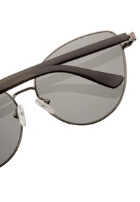 Silmetsällä kehys, jossa on harmaat linssit, kaareva kissamainen muoto ja mustat varret, joissa on kirkkaat nenätyynyt. Minimalistiset suunnittelun yksityiskohdat.