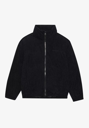 Svart kordfløyels zip-up jakke med høy krage, ribbestruktur og elastisk kant. Har diskret merkevare på brystet.