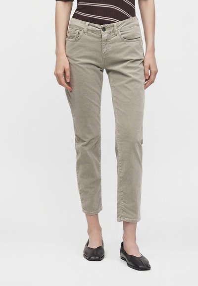 Pantalon court en velours côtelé beige porté avec des ballerines noires à bout pointu et un haut rayé marron foncé.