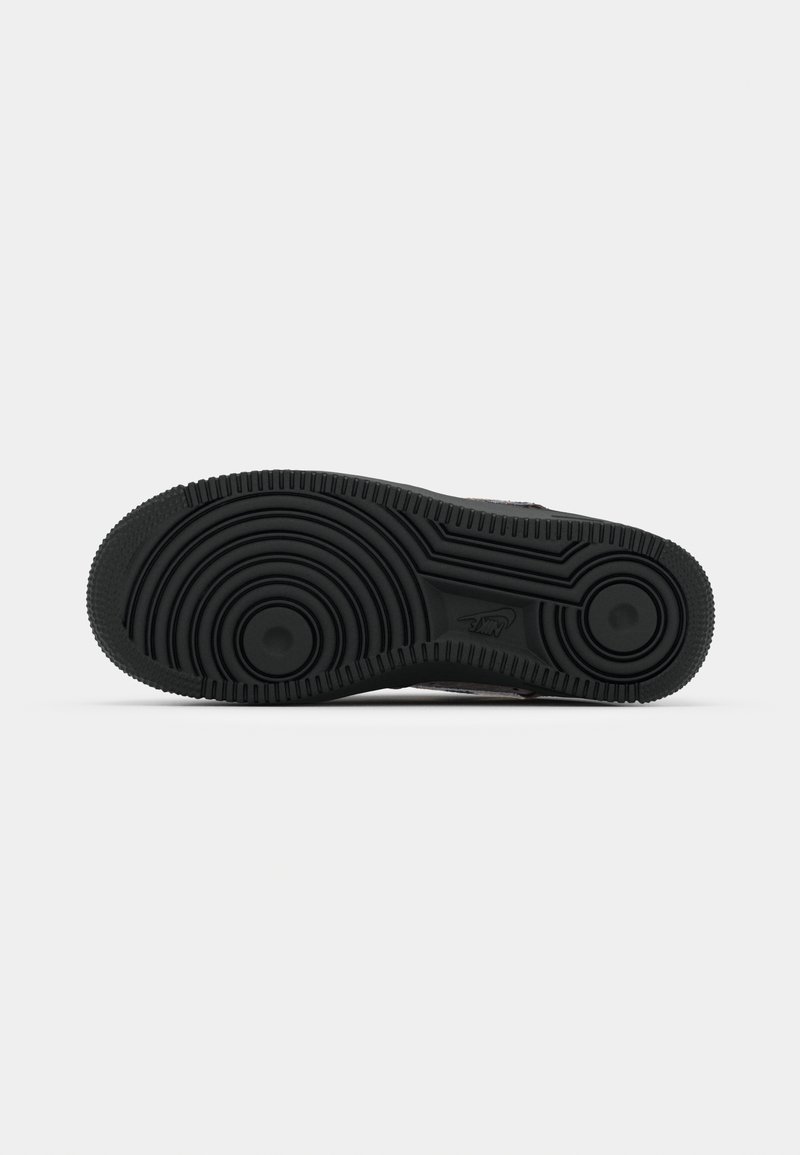 Schwarze Sneaker-Sohle mit kreisförmigen Mustern, strukturiertem Oberflächen und leicht erhöhten Akzentbereichen. Gummimaterial mit tiefem Profil für besseren Halt.