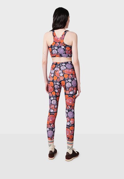 Ensemble de brassière de sport et de leggings avec un motif floral en violet, orange et noir. Fabriqué en tissu extensible, il présente un design ajusté et des bretelles larges.