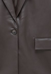 Blazer en cuir marron foncé vu de face avec un bouton, partie du col cranté et une poche à rabat sur le côté droit.